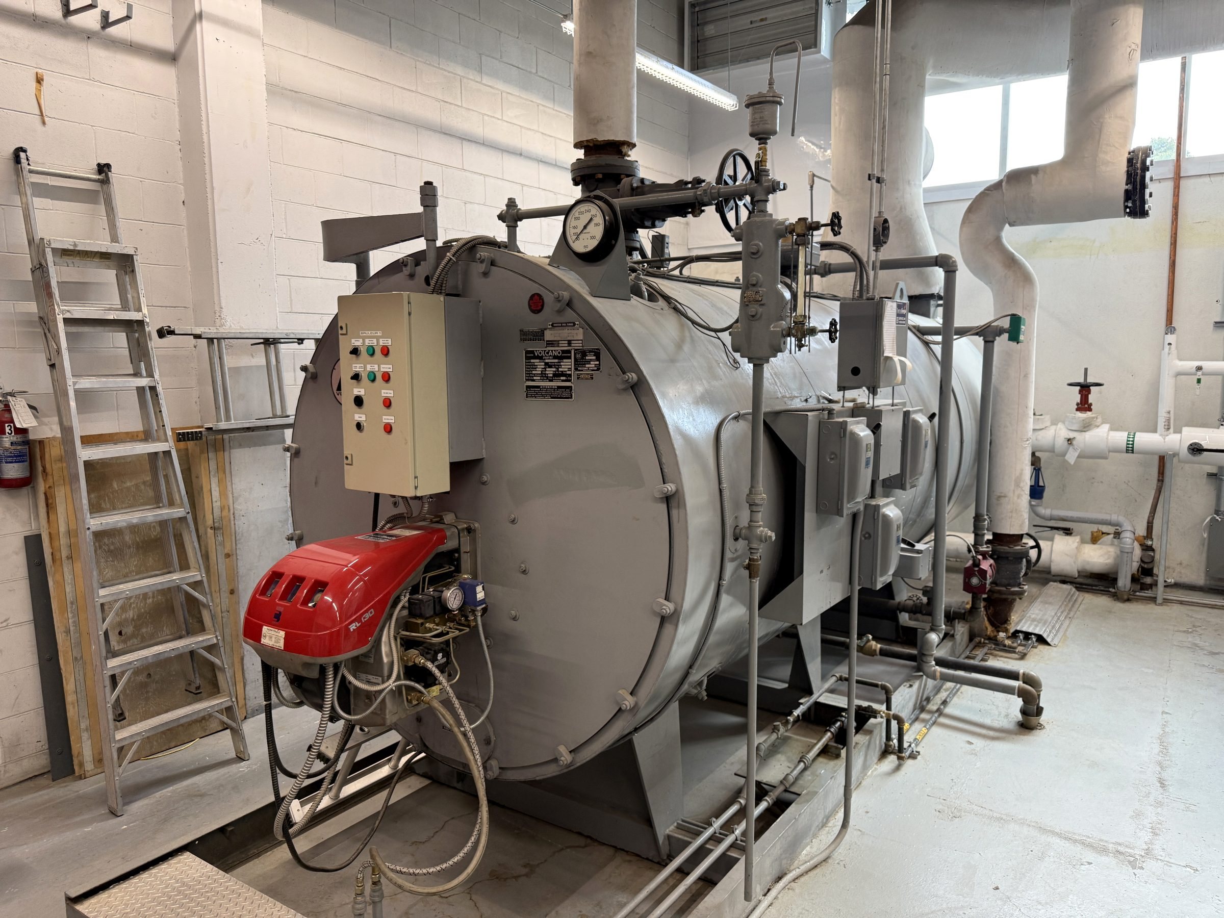 Chaudière avec son brûleur au gaz dans une salle mécanique, entretenue par Services Techniques NRJ